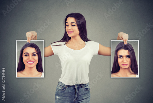 woman holding pictures with good and bad emotions having mood swings and smiling at positive herself