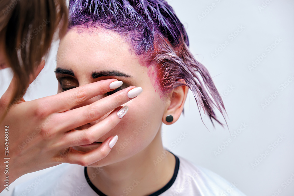 Naklejka premium Beautiful girl with violet hair on white background master in make-up.