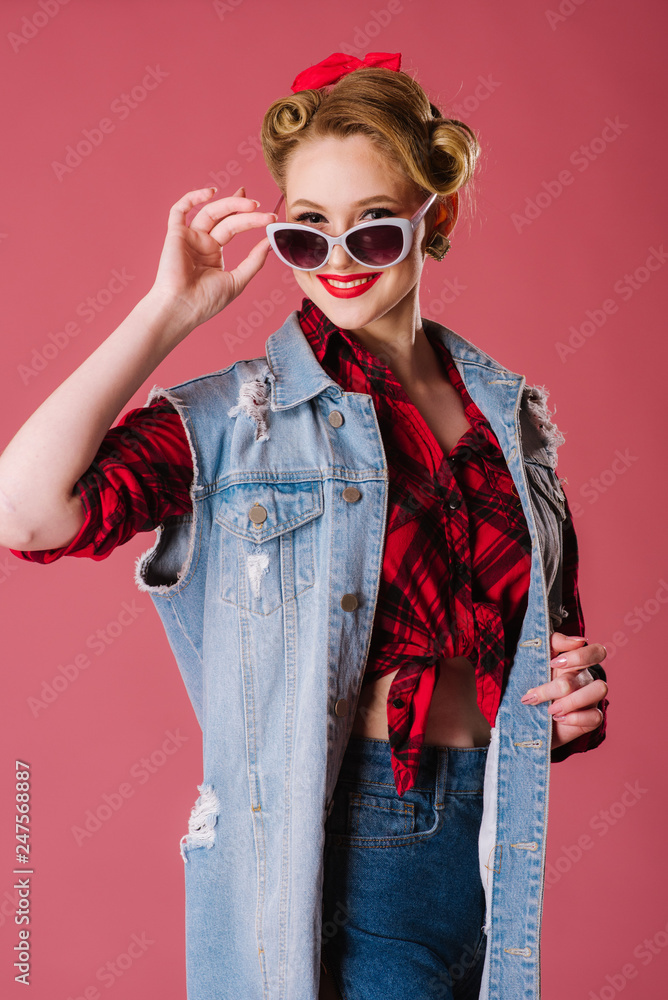 Plakat Ładna młoda kobieta jest ubranym szkła i pozuje na różowym tle w retro stylu. Portret pinup