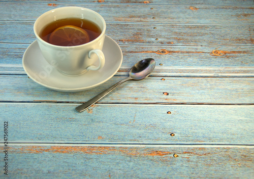 A cup of tea with a slice of lison and a spoon lie on a wooden table. photo