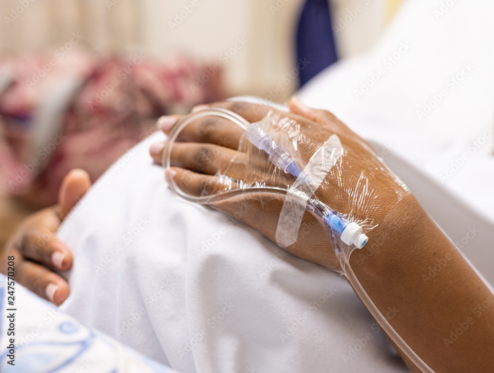 Φωτογραφία An image of a pregnant lady lying in a hospital bed holding her tummy, with a cl