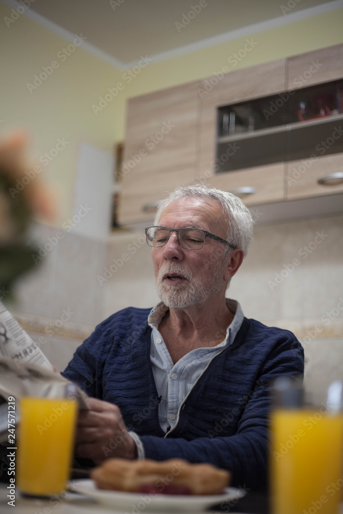 Old man reading newspapers and drinking orange juice. Old man reading newspapers and drinking orange juice.