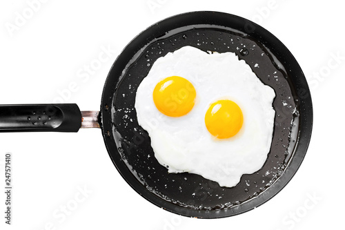 Two fried eggs in a frying pan cooked for breakfast. Delicious international meal isolated on a white background.