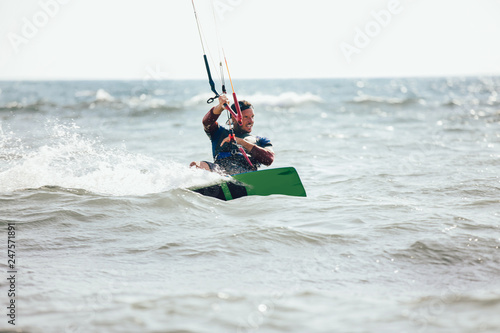 Professional kiter makes the difficult trick on a beautiful background. Kitesurfing Kiteboarding action photos man among waves quickly goes