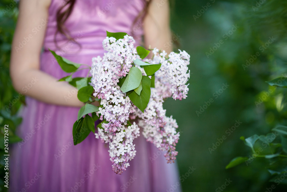 Bouquet of spring lilac flowers in young girls hands on green background. Close up picture Bouquet of spring lilac flowers in young girls hands on green background. Close up picture