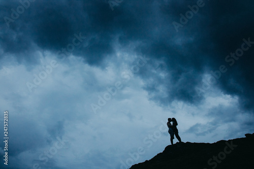 Ein küssendes und sich liebendes Paar vor romantischen Wolken