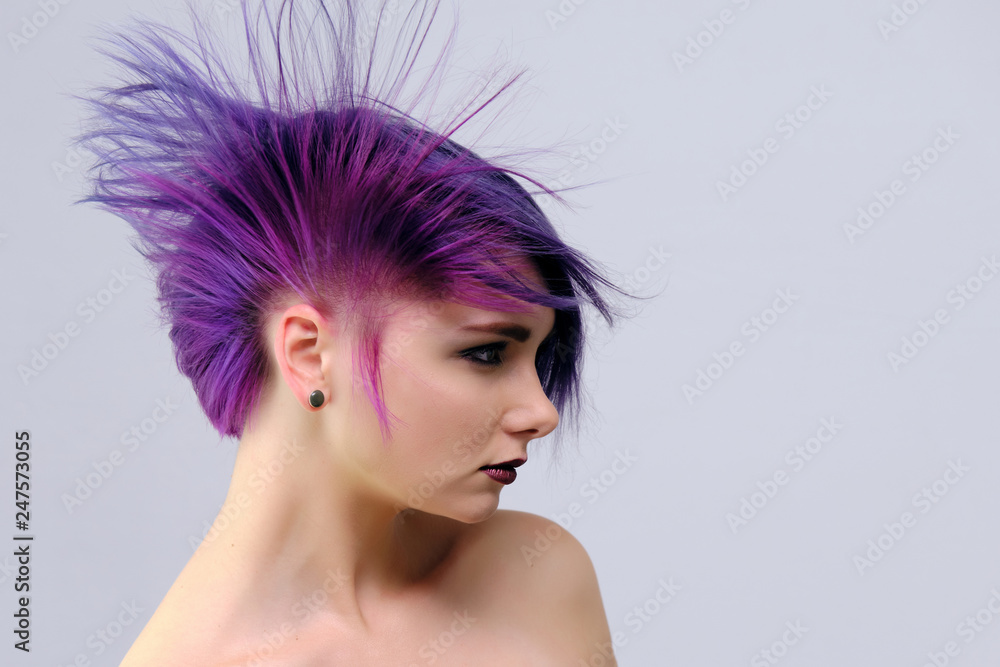 A beautiful, sexy girl with purple hair and a short haircut sits in the middle of the photo with a white background A beautiful, sexy girl with purple hair and a short haircut sits in the middle of the photo with a white background