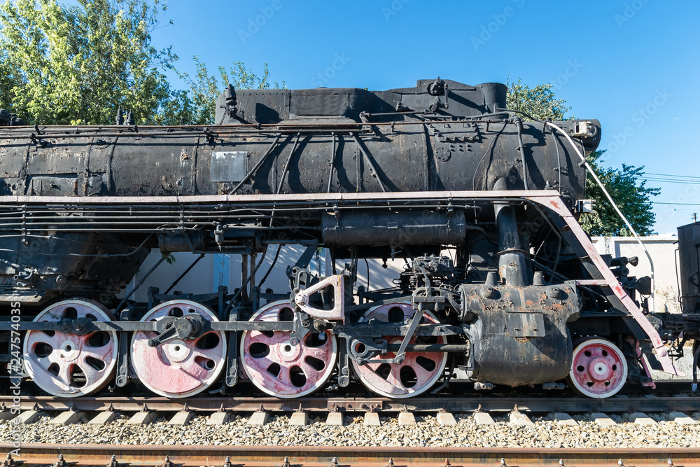 Old rusty steam locomotive beside a railway station platform. Retro train. Old rusty steam locomotive beside a railway station platform. Retro train.