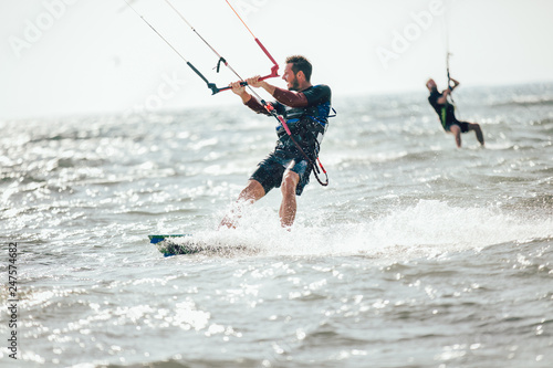 Professional kiter makes the difficult trick on a beautiful background. Kitesurfing Kiteboarding action photos man among waves quickly goes