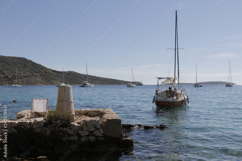 Sailboats, yachts on the Adriatic Sea. Beautiful weather. Sunny, hot, summer day on the Croatian coast. Primosten, Croatia, rocky shore, rock, mediterranean vegetation, seashore.