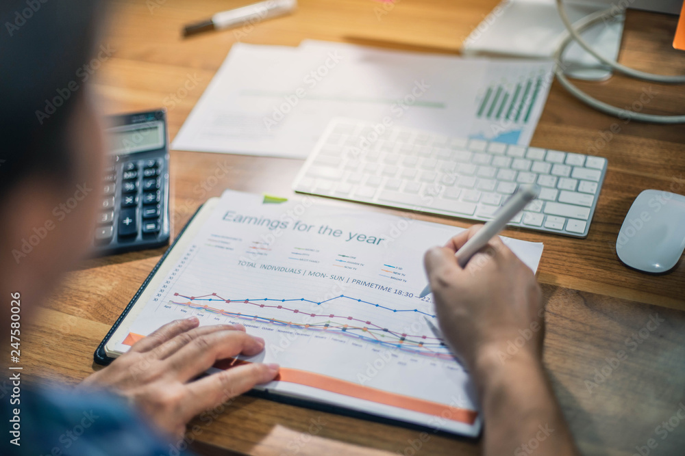 Businessman is reviewing a financial report for a return on investment or investment risk analysis. Businessman is deeply reviewing investment charts. Businessman is reviewing a financial report for a return on investment or investment risk analysis. Businessman is deeply reviewing investment charts.