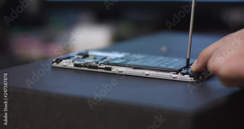 Repairman disassembling smartphone with screwdriver. Technician fixing broken phone, electronics repair service, repairer pov