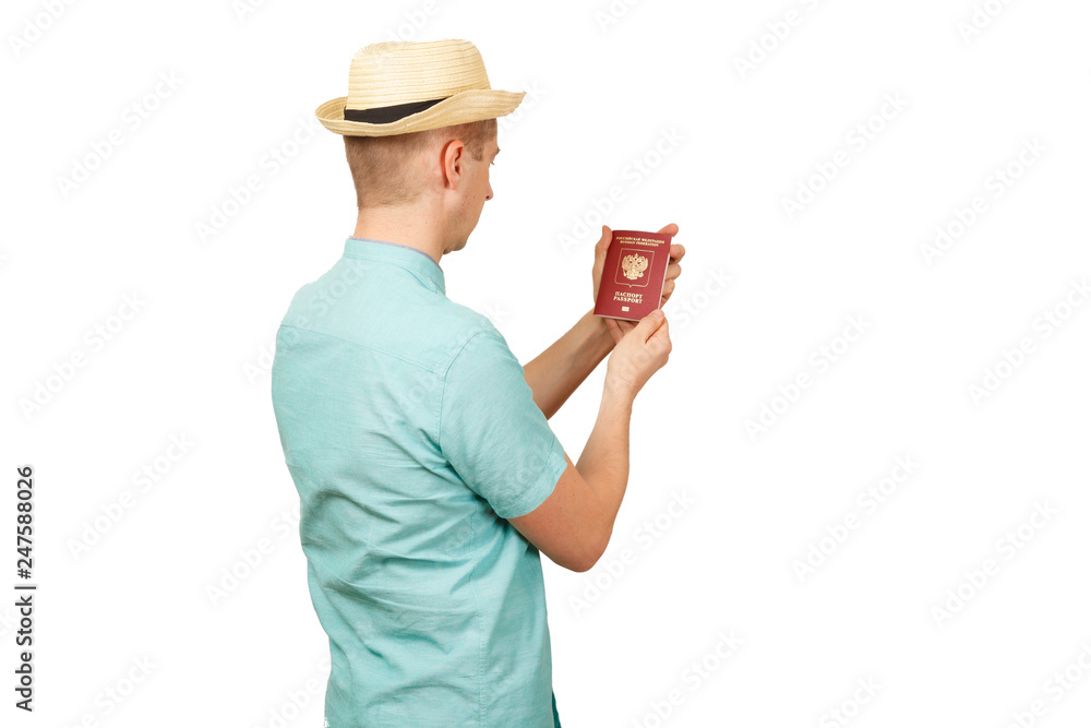 The man looks in the opened international passport. in a summer shirt, a hat. The rear view, from a back The man looks in the opened international passport. in a summer shirt, a hat. The rear view, from a back