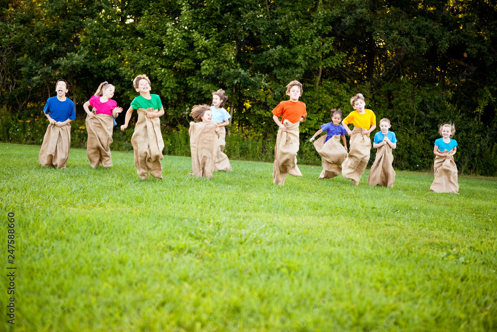 Obraz premium Happy Kids Having Potato Sack Race Outside