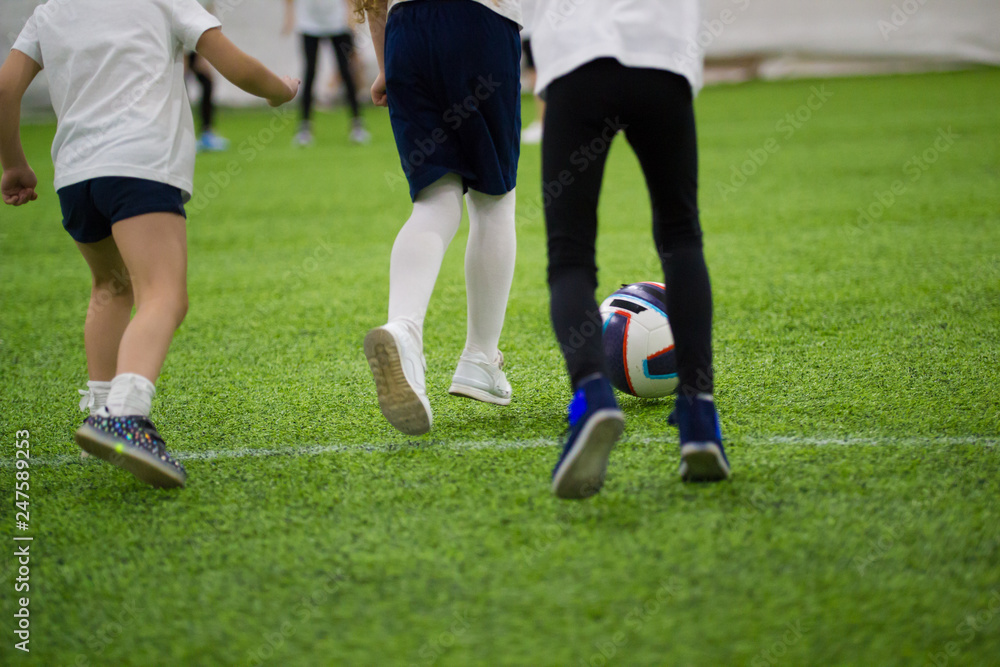 Children playing football indoors. Kids running on the field