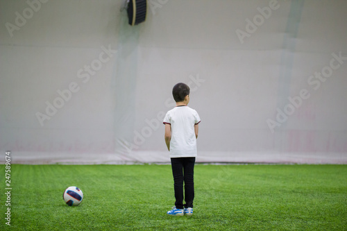 Playing football indoors. A little boy standing on a football field