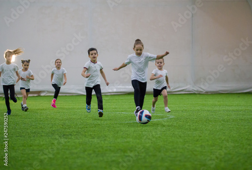 Little kids playing football indoors. Children football team playing on the field