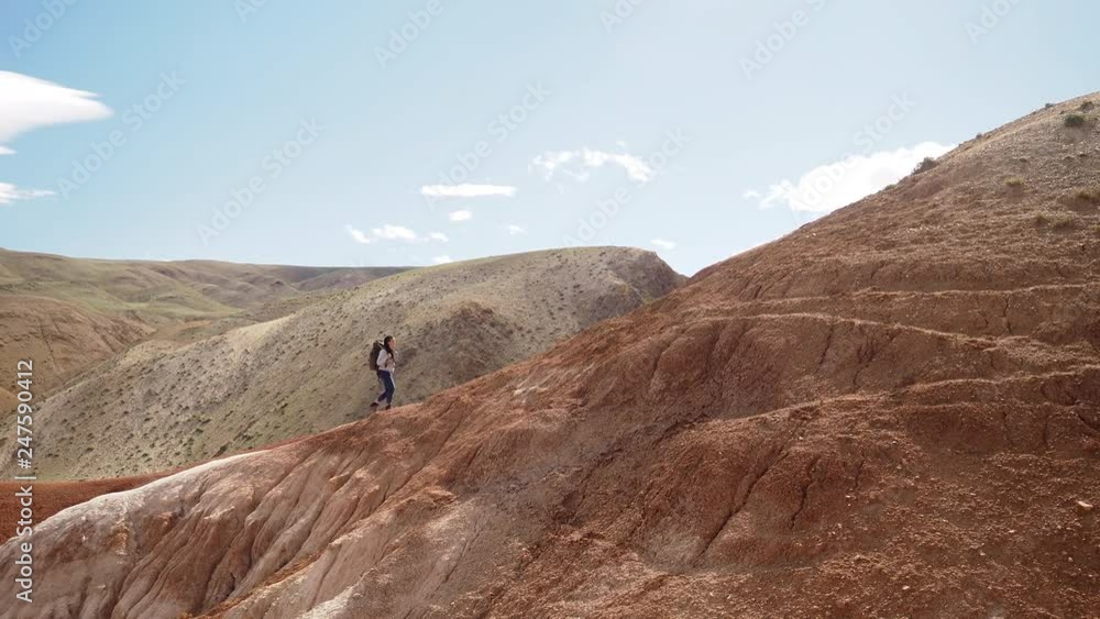 One young woman going to the high hill on the rock way. Scenery red mountain background, silent and lonely place for the strong and courage trek. Successful endurance female person enjoy the journey One young woman going to the high hill on the rock way. Scenery red mountain background, silent and lonely place for the strong and courage trek. Successful endurance female person enjoy the journey