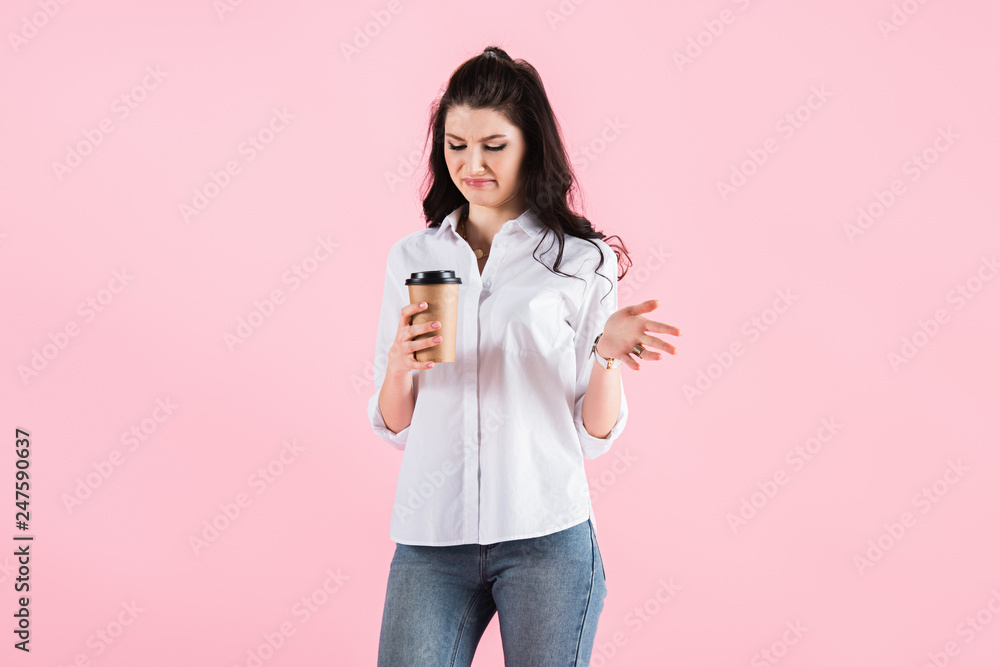 confused brunette girl looking at paper cup with coffee, isolated on pink confused brunette girl looking at paper cup with coffee, isolated on pink