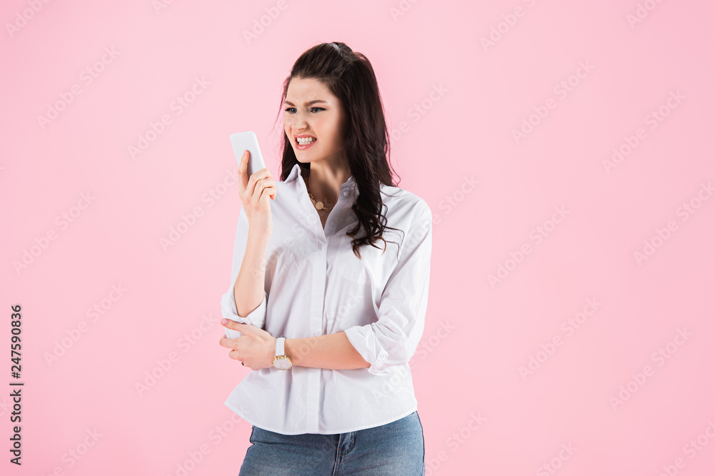 beautiful angry girl looking at smartphone, isolated on pink beautiful angry girl looking at smartphone, isolated on pink