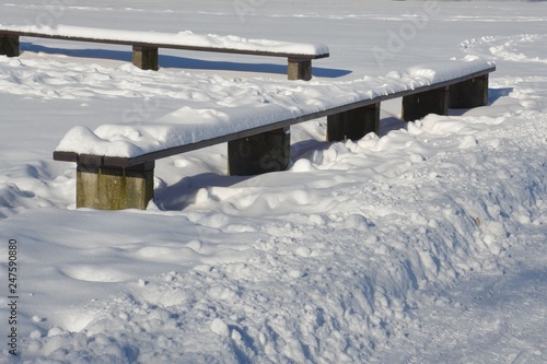 Holzbank im winterlichen Stadtpark schneebedeckt
