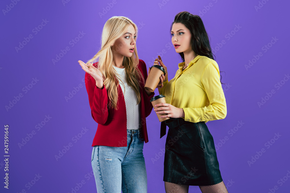 Girls talking with interest and drinking coffee on purple background Girls talking with interest and drinking coffee on purple background