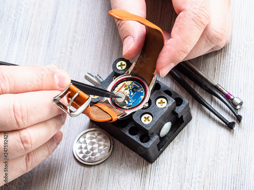 watchmaker installs battery in quartz wristwatch photo