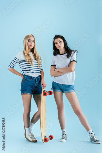 Fotografija Winsome girls posing with longboard on blue background