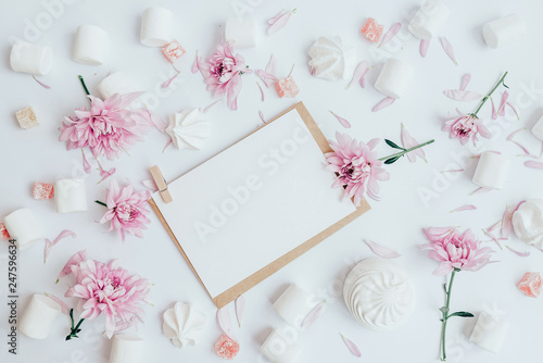 White sheet on the table. Around white marshmallows and pink flower