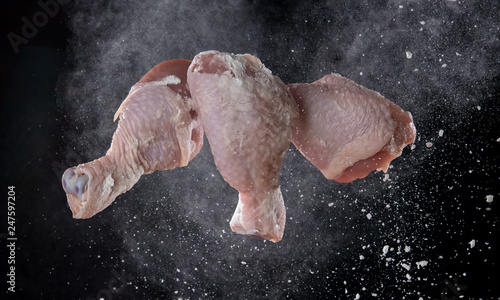 Chicken leg with flour splash or explosion flying in the air on black background Stop motion