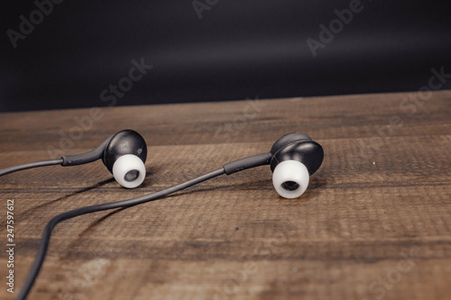 black earbud headphones on wooden background
