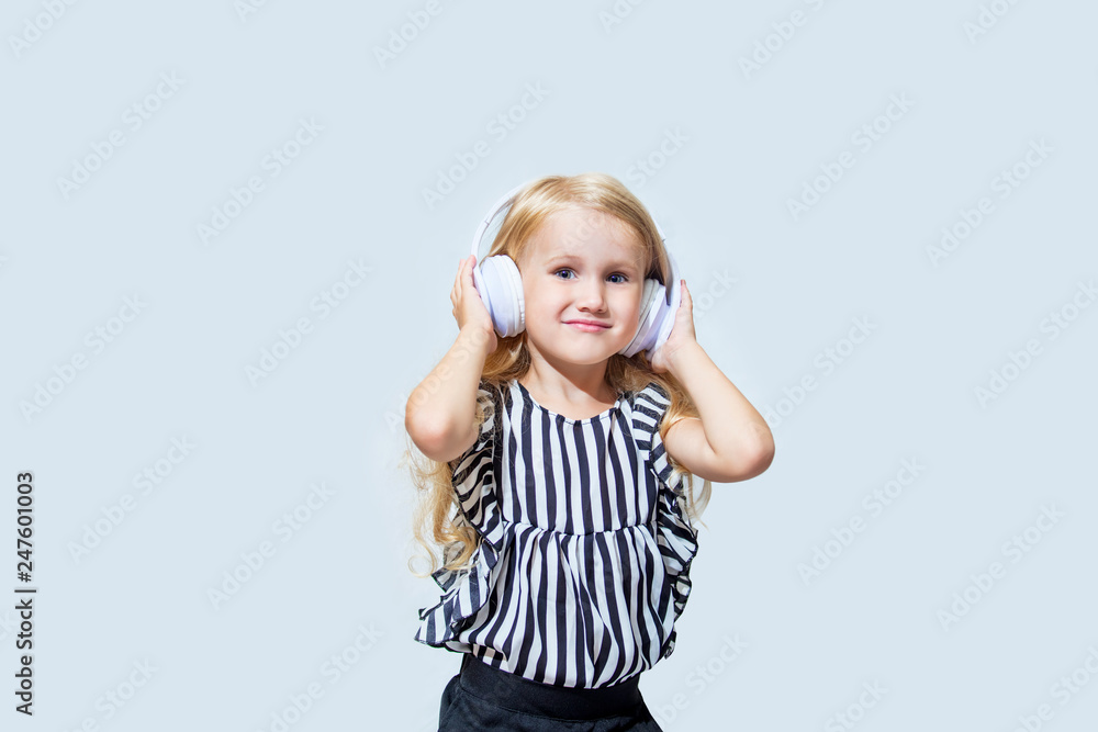 Little child girl beautiful fashion and happy in the white earphones listening to music on an isolated background Little child girl beautiful fashion and happy in the white earphones listening to music on an isolated background