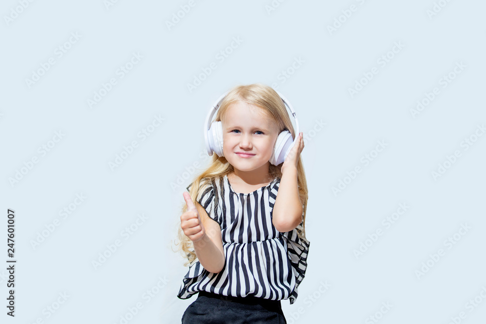 Little child girl beautiful fashion and happy in the white earphones listening to music on an isolated background Little child girl beautiful fashion and happy in the white earphones listening to music on an isolated background