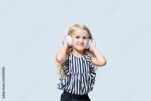 Little child girl beautiful fashion and happy in the white earphones listening to music on an isolated background