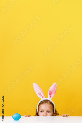 Canvas Print Cute little child girl with bunny ears at home is hunting for Easter eggs