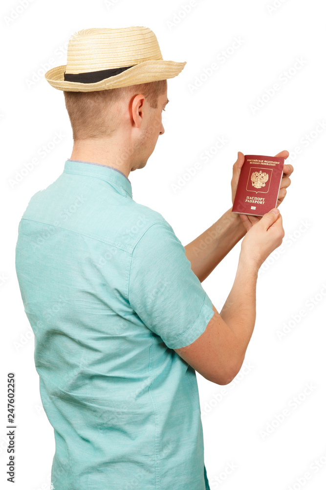 The man looks in the opened international passport. in a summer shirt, a hat. The rear view, from a back The man looks in the opened international passport. in a summer shirt, a hat. The rear view, from a back