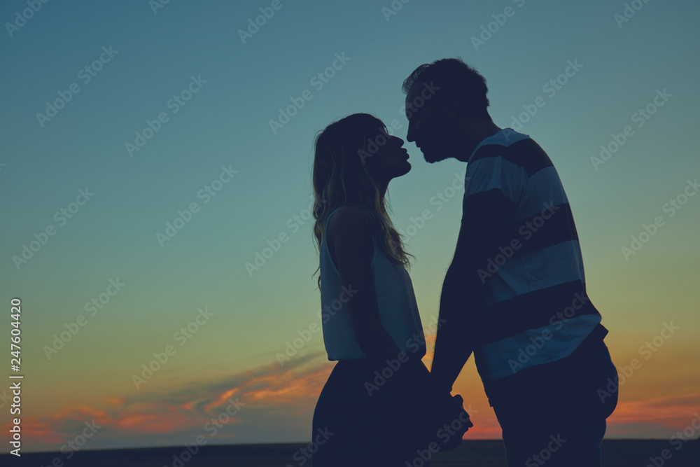 Silhouettes of a couple in sunset / sunrise time.