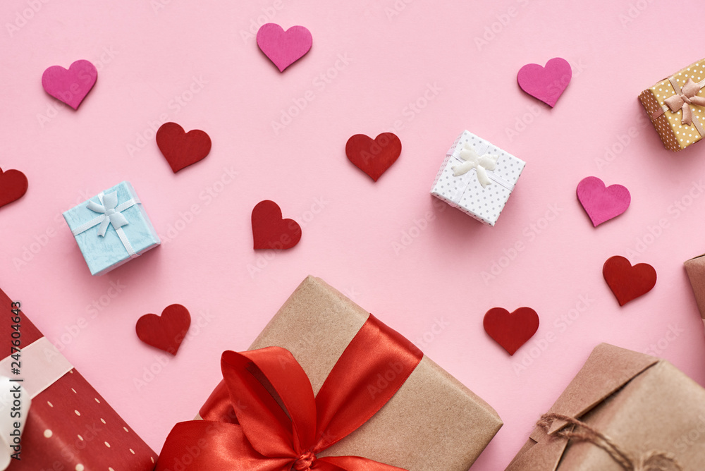 Love is in the air. Different types of gift boxes with decorative paper hearts on pink background.
