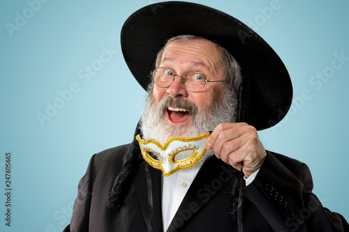 Portrait of a senior orthodox Hasdim Jewish man with wooden Grager Ratchet at Jewish festival of Purim at studio. The purim, jewish, festival, holiday, celebration, judaism, pastry, tradition, cookie photo