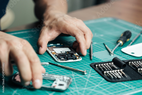 Electronics repair service. Technician disassembling smartphone for inspecting