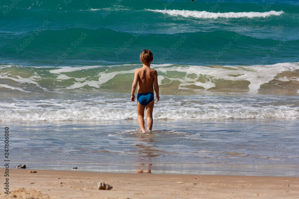the child stands in the sea in front of the waves the child stands in the sea in front of the waves