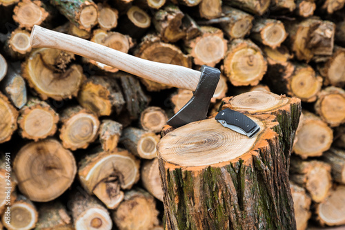 axe and jackknife case on the stump, firewoods on the background photo