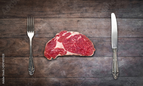 Vászonkép slice red meat / raw steak with knife and fork on wooden background