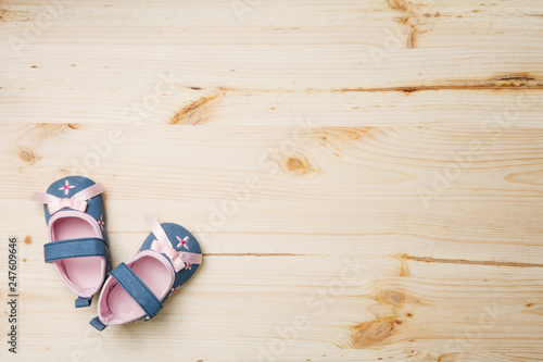 A pair of cute pink and blue baby girl shoes on wooden background, copy space