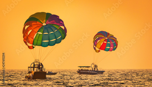 amazing shot at sunset of Parasailing water amusement - flying on a parachute behind a boat on a summer holiday by the sea in the resort Baga beach Goa India India watersports