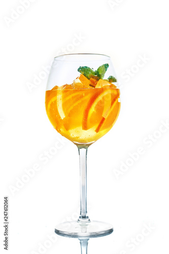 orange cocktail in wine glass with mint on white background