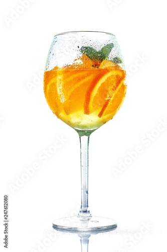 orange cocktail in wine glass with mint on white background. misted glass