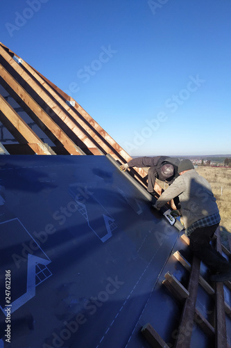The worker stapler attaches to the rafter gidrobarier on the background can see the sky