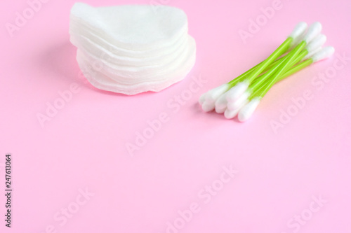 Clean cotton stack of disk for beauty hygiene with selective focus and individual ear sticks with sterile softness applicator on pink neutral background. Ear swabs and face sponges for health