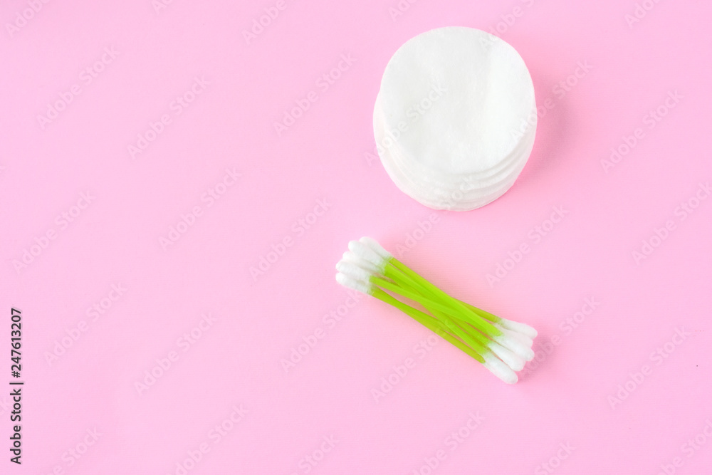 Clean cotton stack of disk for beauty hygiene with selective focus and individual ear sticks with sterile softness applicator on pink neutral background. Ear swabs and face sponges for health Clean cotton stack of disk for beauty hygiene with selective focus and individual ear sticks with sterile softness applicator on pink neutral background. Ear swabs and face sponges for health